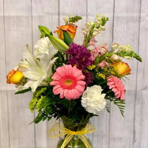 Mixed bouquet in a glass vase with a yellow ribbon