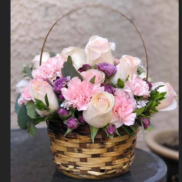 Basket of pink and white roses with purple carnations