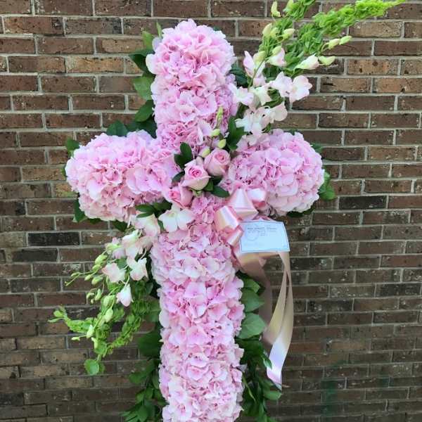 Standing cross of pink hydrangeas with pink roses and green bells of Ireland on an easel.