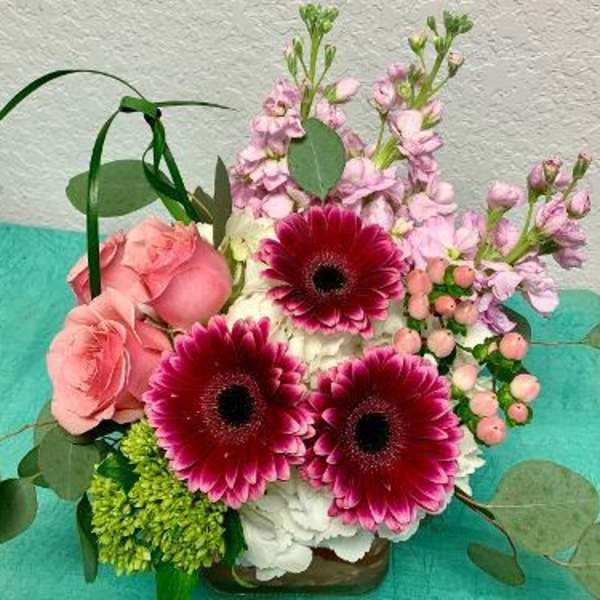 Pink roses and magenta gerbera daisies in a low vase arrangement