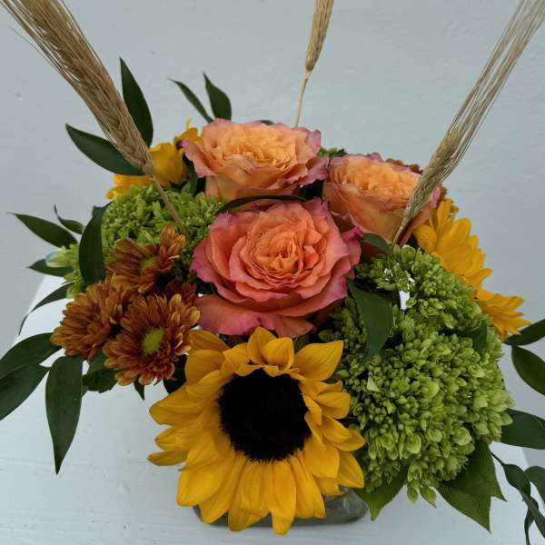 Bouquet of peach roses, sunflowers, and green hydrangeas with wheat stems