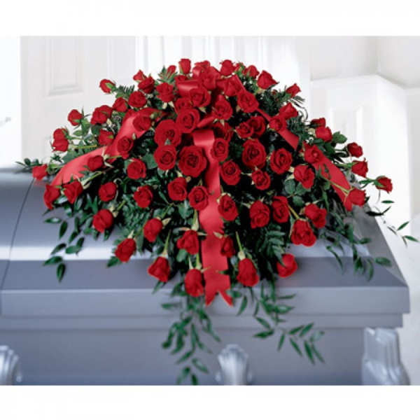 Large spray of red roses with red ribbon displayed on a gray casket.