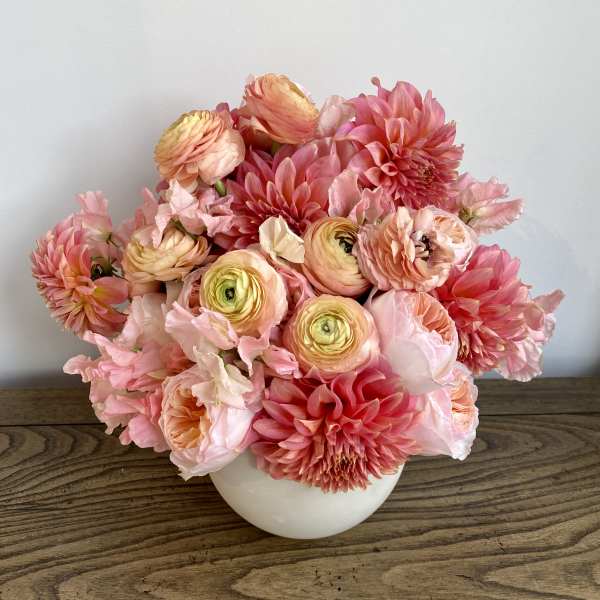 Pink and peach flowers arranged in a white vase