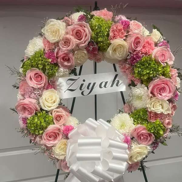 Heart-shaped floral wreath with pink and white roses and a white bow