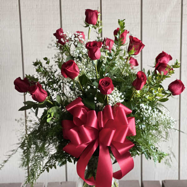 Red roses in a clear vase with a large red ribbon bow