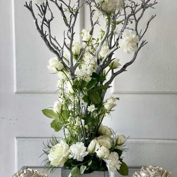 Tall white floral arrangement with branches in a gray container