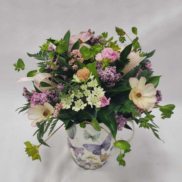 Mixed pink and cream flowers in a butterfly-patterned mug vase