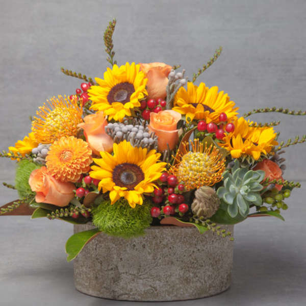 Sunflower and peach rose arrangement in a stone vase