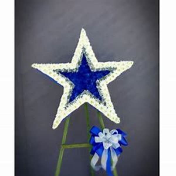 Blue and white star-shaped floral tribute on a stand with a ribbon bow