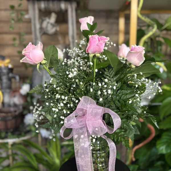 Pink roses in a glass vase with a pink ribbon