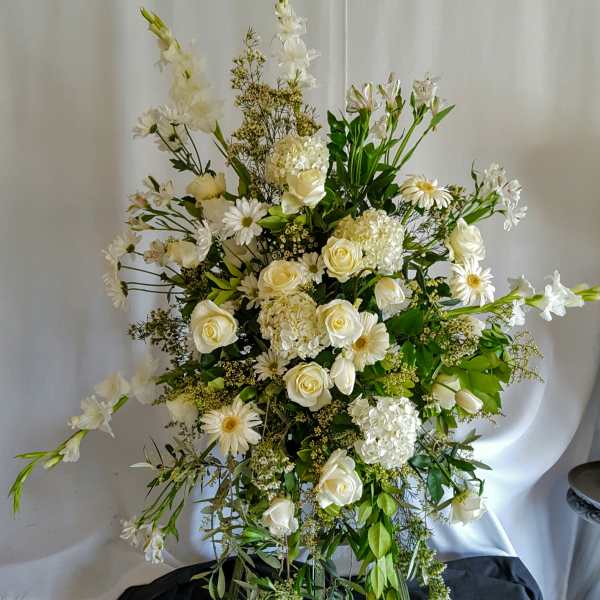 Tall white floral arrangement with roses, daisies, and lilies