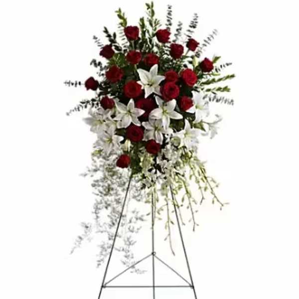 Standing floral spray with red roses and white lilies on an easel