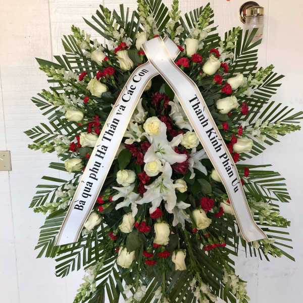 Standing funeral wreath with white roses, lilies, and red carnations