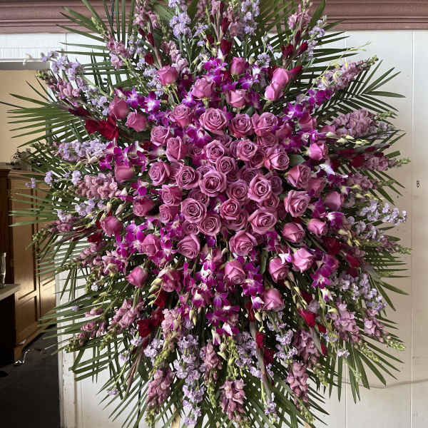 Large standing spray of pink roses and purple orchids with palm fronds