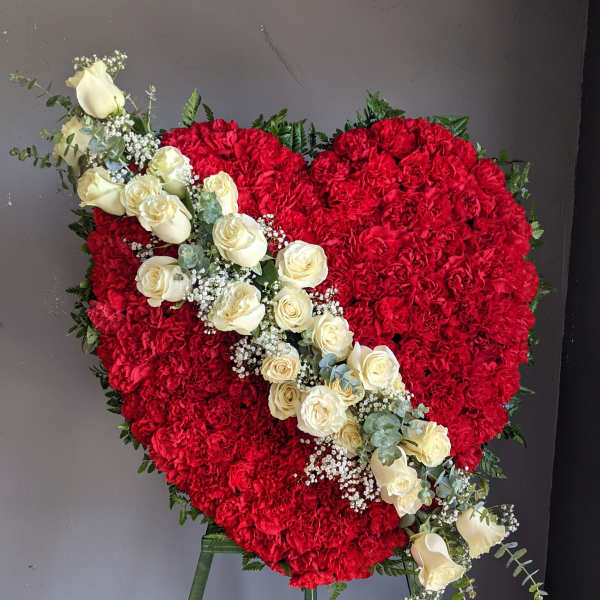 Heart-shaped red floral arrangement with a diagonal spray of white roses