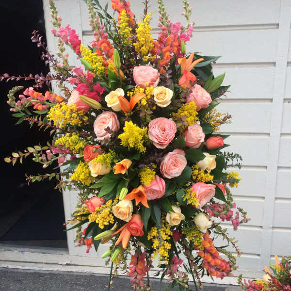 Tall standing floral spray with pink roses, orange lilies, and yellow filler flowers