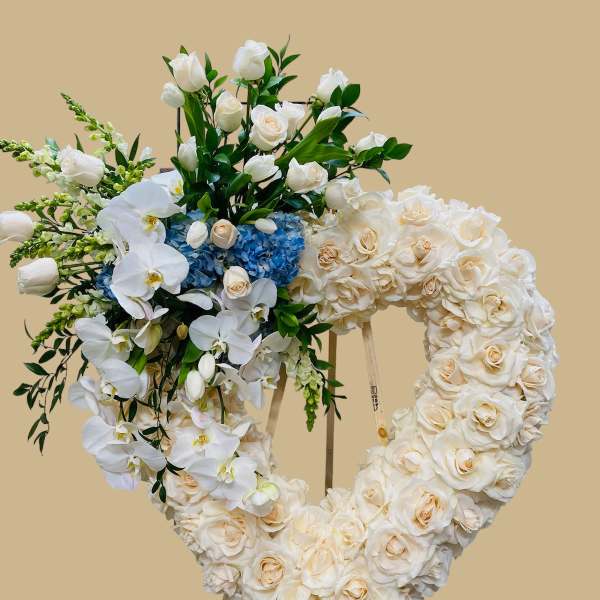 Heart-shaped floral wreath on an easel with white roses and orchids