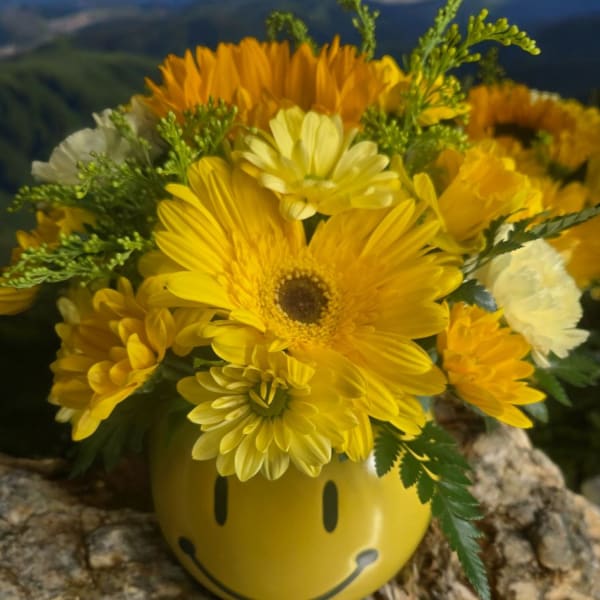 Yellow flower bouquet in a smiley-face vase
