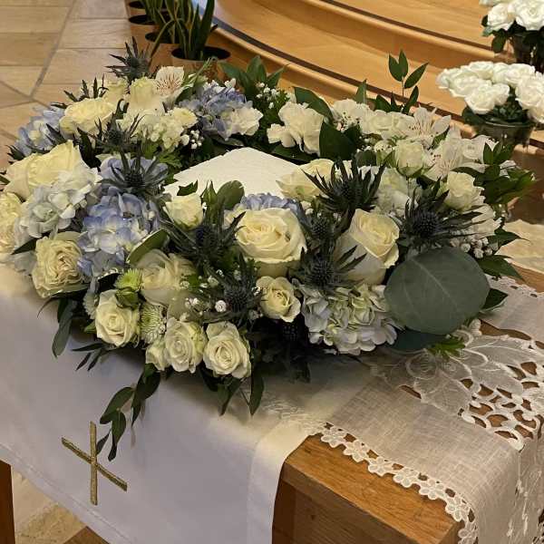 White floral casket spray with roses and hydrangeas