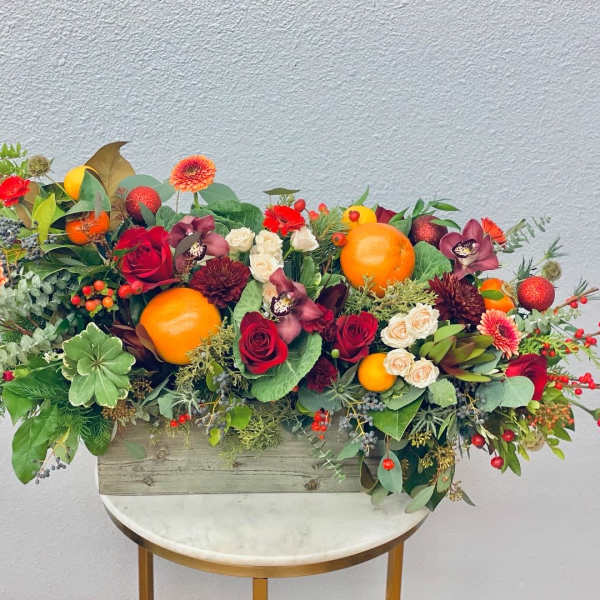 Mixed floral arrangement with oranges in a wooden box