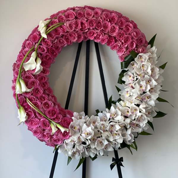 Pink rose wreath with white orchids and calla lilies on a black stand