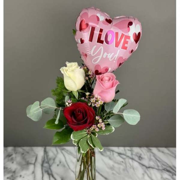 Roses in a glass vase with a pink heart balloon