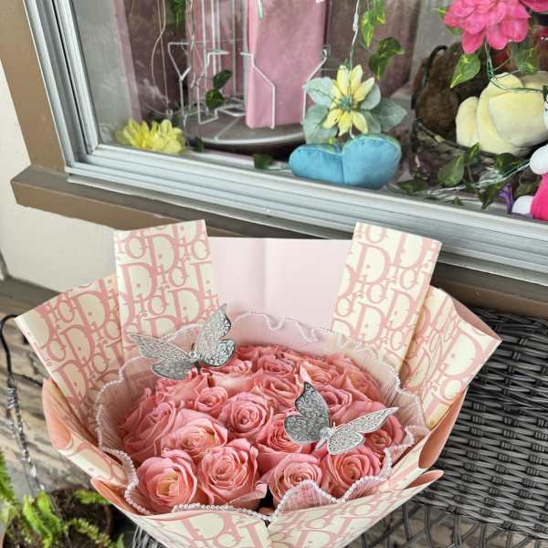 Bouquet of pink roses wrapped in patterned paper with a pink ribbon