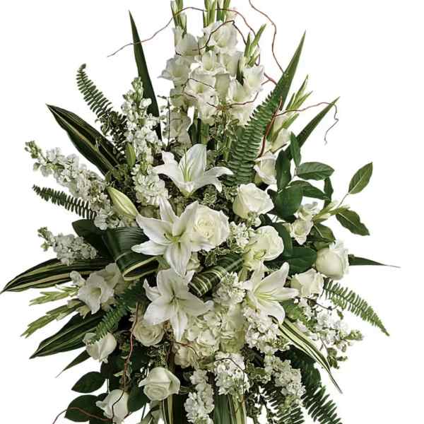 White floral standing spray with lilies and roses on a black easel