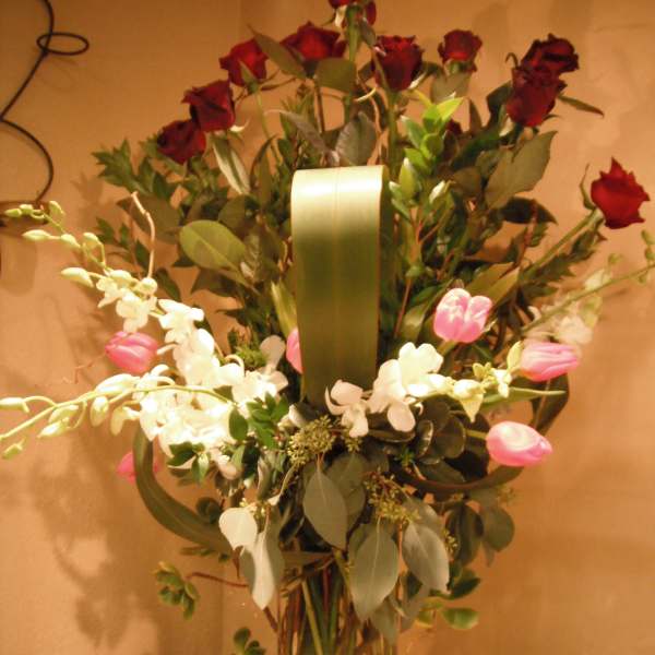 Tall bouquet of red roses and white orchids in a clear glass vase
