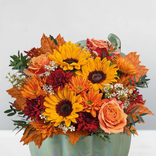 Autumn bouquet of sunflowers, roses, and mums in a pumpkin-shaped vase