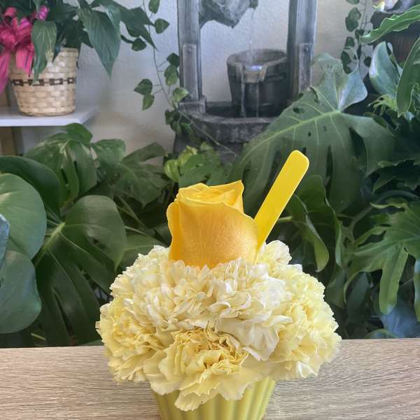 Yellow rose and cream carnations in a green cup with a yellow pick