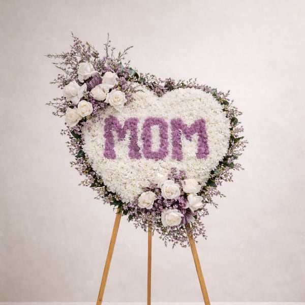 Heart-shaped floral easel tribute with "MOM" in purple flowers