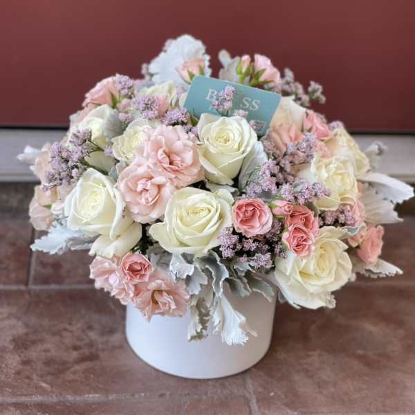 Pink and white roses arranged in a white box