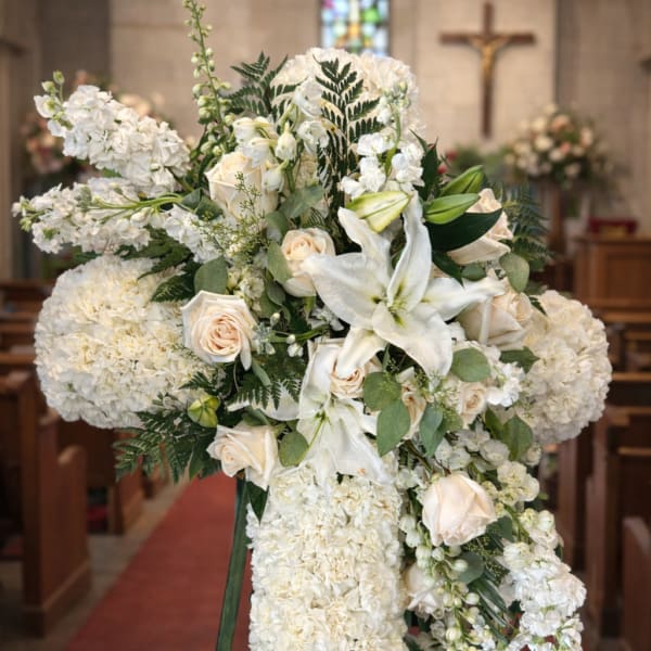 White floral funeral spray on an easel in a church