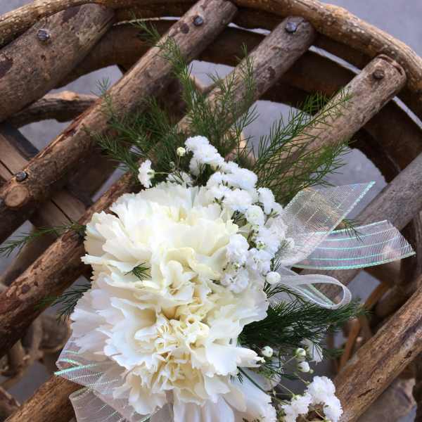 White carnation corsage with ribbon and greenery