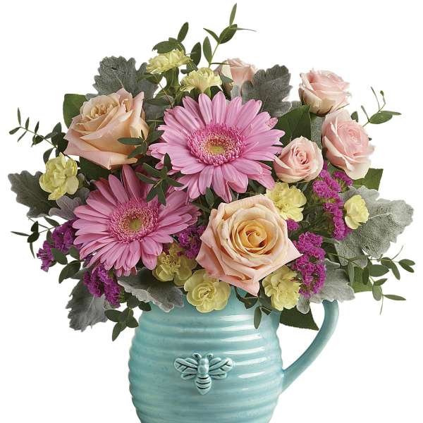 Pink gerbera daisies and roses in a turquoise mug vase