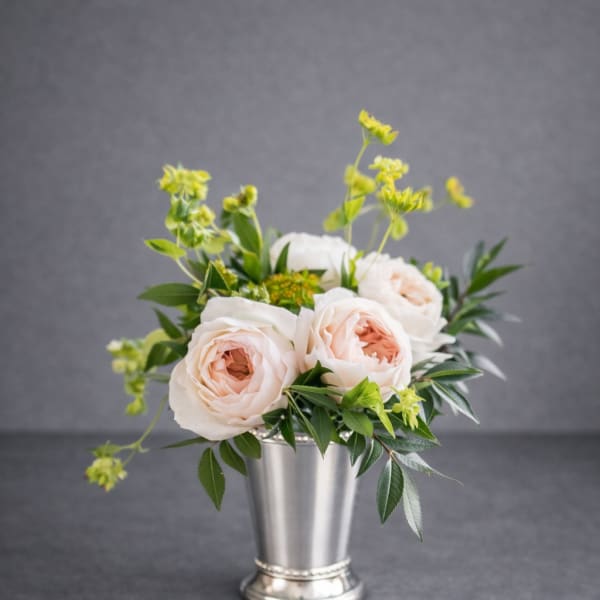 Blush roses in a silver vase with green accents
