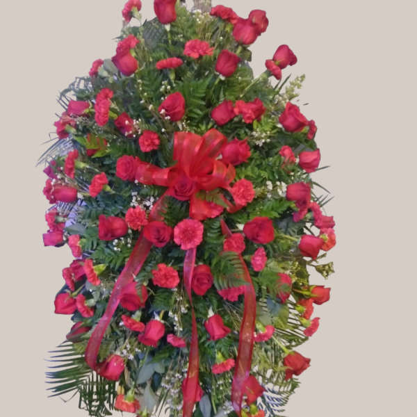 Standing floral spray of red roses and carnations with ribbon