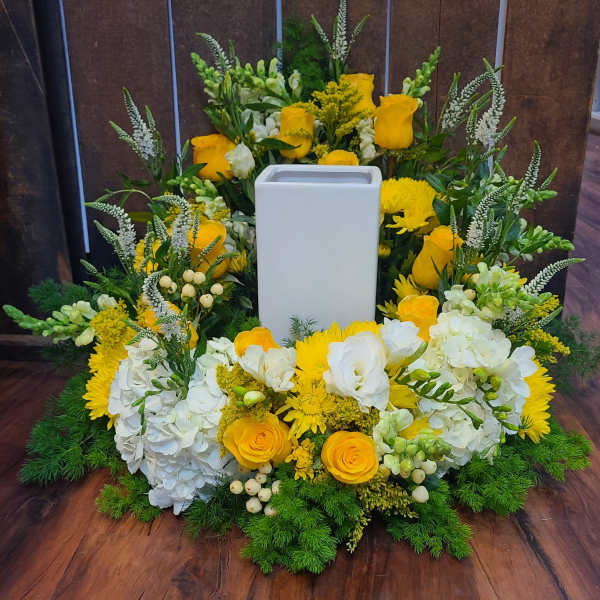 Yellow and white floral ring arrangement encircling a tall white rectangular vase