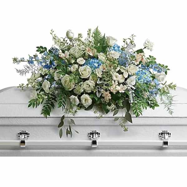 White and blue floral casket spray on a white coffin