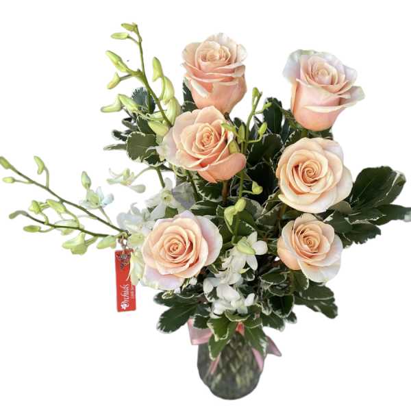 Peach roses with white orchids in a glass vase