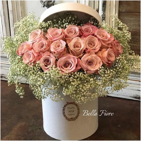 Pink roses arranged in a white hatbox with baby's breath