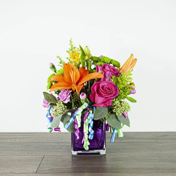 Bouquet of orange lilies and pink roses in a purple glass vase