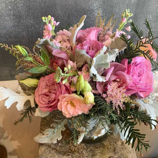 Pink and peach floral arrangement in a glass vase with silvery foliage
