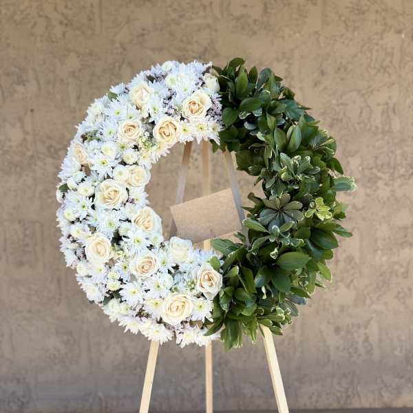 White floral wreath with cream roses on a wooden easel