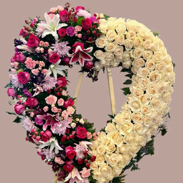 Heart-shaped floral wreath with cream and pink flowers on a stand