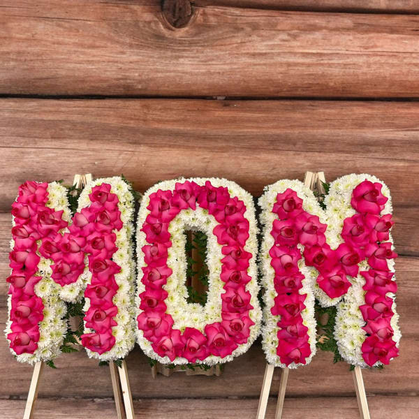 Floral standing tribute spelling MOM in pink and white flowers
