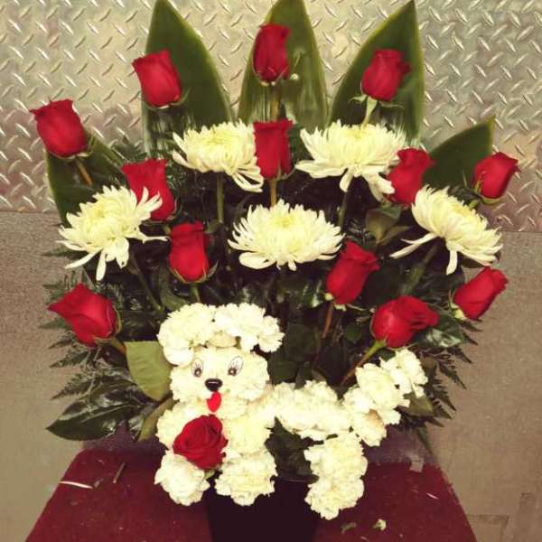 Red roses and white chrysanthemums arranged around a teddy bear in a black vase