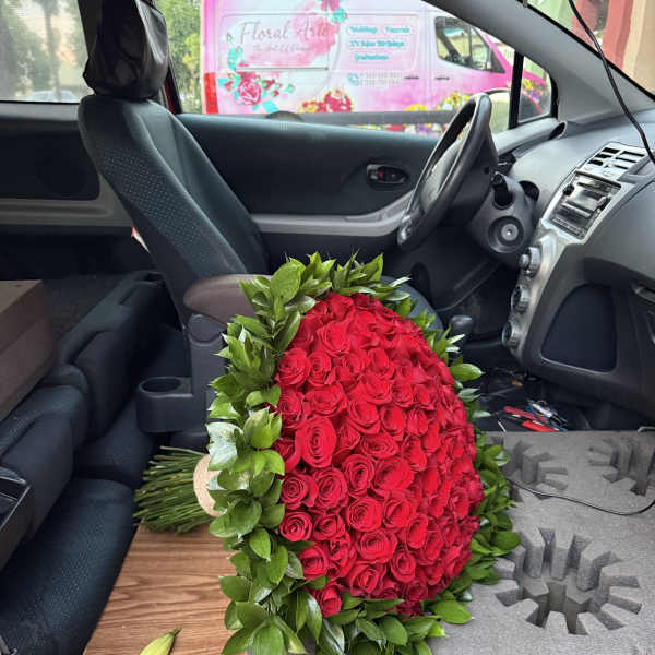 Large red rose bouquet with green foliage in a car interior