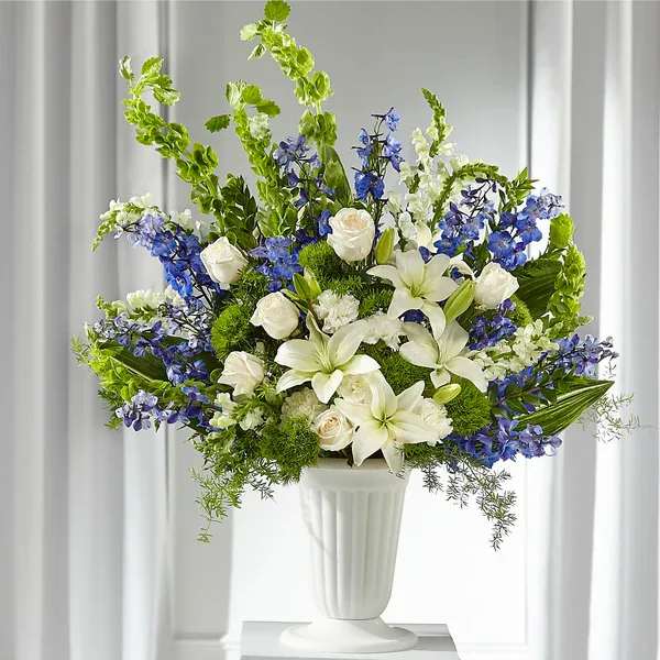 White and blue floral arrangement in a white pedestal vase